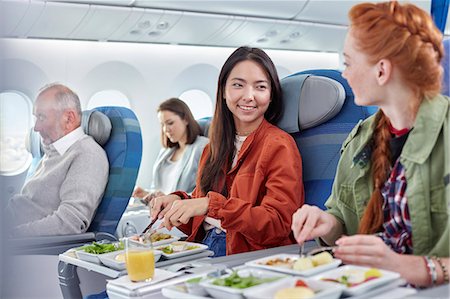 Women friends eating dinner and talking on airplane Stock Photo - Premium Royalty-Free, Code: 6113-09059125
