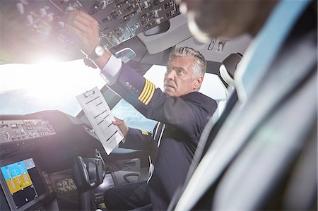 simsearch:6113-09059160,k - Male pilot with clipboard preparing, adjusting instruments in airplane cockpit Photographie de stock - Premium Libres de Droits, Code: 6113-09059137