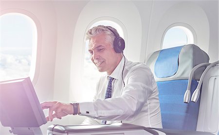 passenger - Businessman with headphones watching movie on airplane Stock Photo - Premium Royalty-Free, Code: 6113-09059204