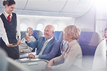 simsearch:6113-07565110,k - Flight attendant serving champagne to mature couple in first class on airplane Stock Photo - Premium Royalty-Free, Code: 6113-09059206