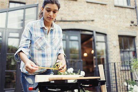 simsearch:6113-06753289,k - Young woman with tape measure measuring wood on patio Photographie de stock - Premium Libres de Droits, Code: 6113-09059236