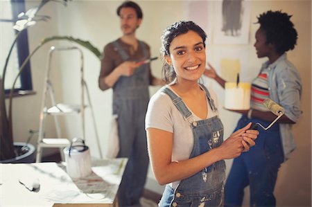 Portrait smiling young woman painting living room with friends Stock Photo - Premium Royalty-Free, Code: 6113-09059316