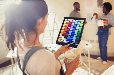 simsearch:632-08545868,k - Young woman with digital tablet viewing digital paint swatches, painting living room Stock Photo - Premium Royalty-Free, Code: 6113-09059323