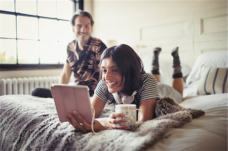 Smiling couple relaxing, drinking coffee and using digital tablet on bed Photographie de stock - Premium Libres de Droits, Code: 6113-09059418