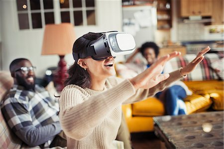 futuristic joy - Woman gesturing, using virtual reality simulator glasses in living room Stock Photo - Premium Royalty-Free, Code: 6113-09059422