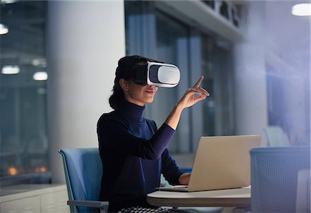 Businesswoman using virtual reality simulator at laptop in office Stock Photo - Premium Royalty-Free, Code: 6113-09004941