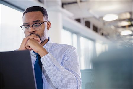 simsearch:6113-07731430,k - Serious, worried businessman working at laptop in office Stock Photo - Premium Royalty-Free, Code: 6113-09004961