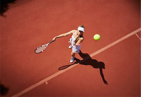 Overhead view young female tennis player playing tennis, serving the ball on sunny clay tennis court Photographie de stock - Premium Libres de Droits, Code: 6113-09005069