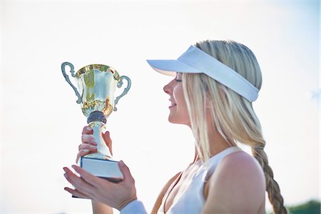 simsearch:649-05648783,k - Blonde young female tennis player in visor holding championship trophy Stock Photo - Premium Royalty-Free, Code: 6113-09005093