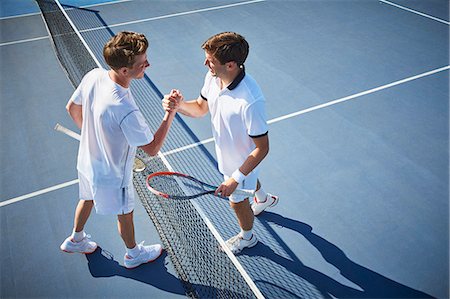 simsearch:6113-09005081,k - Young male tennis players handshaking at tennis net on sunny blue tennis court Stock Photo - Premium Royalty-Free, Code: 6113-09005095