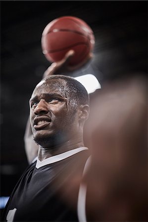 Serious, sweating basketball player holding basketball overhead Stock Photo - Premium Royalty-Free, Code: 6113-09005152