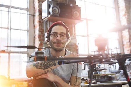 Portrait confident male designer with tattoos working on drone in workshop Photographie de stock - Premium Libres de Droits, Code: 6113-09005195
