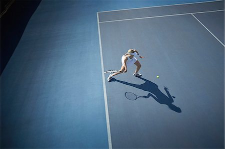 Overhead view young female tennis player playing tennis, hitting the ball on sunny blue tennis court Stock Photo - Premium Royalty-Free, Code: 6113-09005106