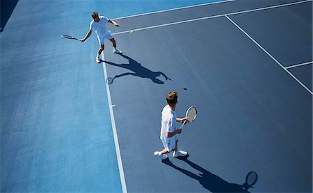 pair - Young male doubles tennis players playing tennis on sunny blue tennis court Stock Photo - Premium Royalty-Free, Code: 6113-09005112