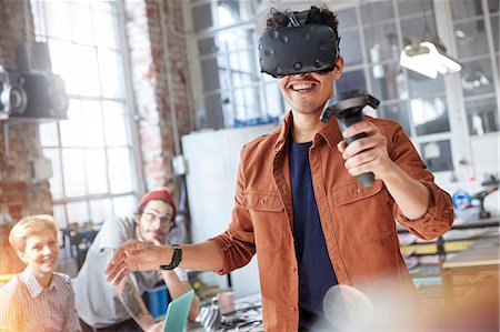 Smiling male computer programmer texting virtual reality simulator glasses and joystick in workshop Stock Photo - Premium Royalty-Free, Code: 6113-09005210