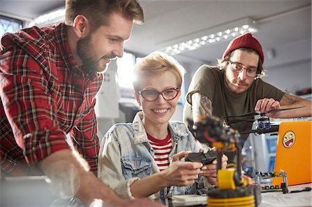 people working together - Smiling computer programmers programming robotics Stock Photo - Premium Royalty-Free, Code: 6113-09005225