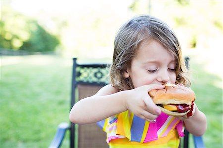 eating burger - Preschool girl eating messy cheeseburger on patio Stock Photo - Premium Royalty-Free, Code: 6113-09005362