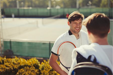 simsearch:6113-09005080,k - Young male tennis players talking above sunny tennis courts Stock Photo - Premium Royalty-Free, Code: 6113-09005391