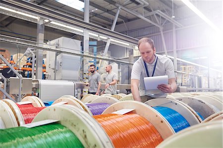 simsearch:6113-09005343,k - Male worker with clipboard checking multicolor spools in fiber optics factory Photographie de stock - Premium Libres de Droits, Code: 6113-09005311