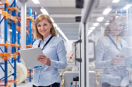 fiber optics and person - Portrait smiling female supervisor with clipboard in fiber optics factory Stock Photo - Premium Royalty-Free, Code: 6113-09005317