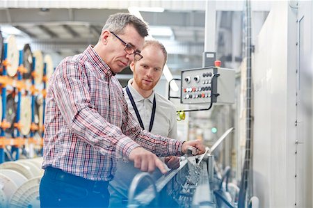 Male supervisor and worker examining machinery in fiber optics factory Stock Photo - Premium Royalty-Free, Code: 6113-09005321