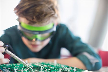 Focused boy student soldering circuit board in classroom Foto de stock - Sin royalties Premium, Código: 6113-09027267