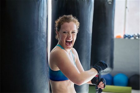 simsearch:6113-09027330,k - Portrait exuberant female boxer screaming, wrapping wrists in gym Fotografie stock - Premium Royalty-Free, Codice: 6113-09027307