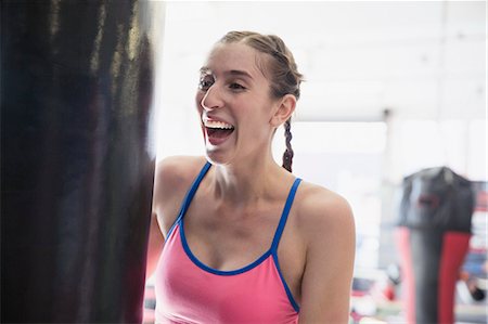 simsearch:6113-09027330,k - Laughing young female boxer at punching bag in gym Fotografie stock - Premium Royalty-Free, Codice: 6113-09027319