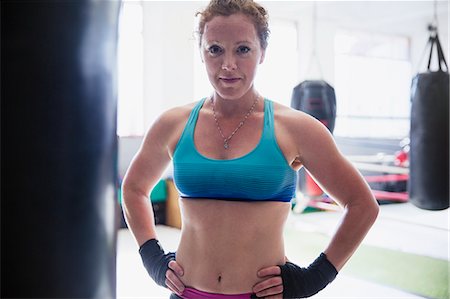 simsearch:6113-09027334,k - Portrait confident, tough female boxer standing at punching bag in gym Photographie de stock - Premium Libres de Droits, Code: 6113-09027326