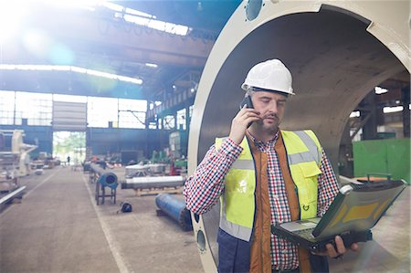 Male engineer with laptop talking on cell phone in steel factory Photographie de stock - Premium Libres de Droits, Code: 6113-09027491