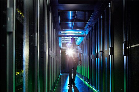 Male security guard with flashlight walking in dark server room Stock Photo - Premium Royalty-Free, Code: 6113-09027560