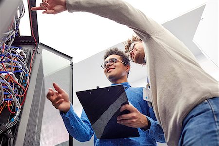 Male IT technicians with clipboard talking at panel in server room Stock Photo - Premium Royalty-Free, Code: 6113-09027573