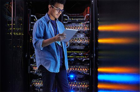 simsearch:6113-09027597,k - Focused male IT technician using digital tablet at panel in dark server room Stock Photo - Premium Royalty-Free, Code: 6113-09027574