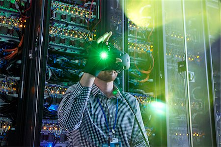 simsearch:6113-09027625,k - Male computer programmer using virtual reality simulator glasses and glowing glove in server room Stock Photo - Premium Royalty-Free, Code: 6113-09027575