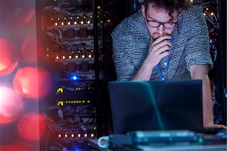 Focused male IT technician working at laptop in dark server room Stock Photo - Premium Royalty-Free, Code: 6113-09027576