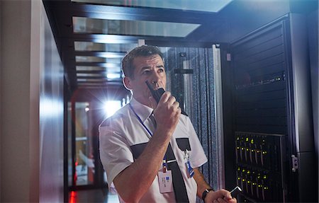 Male security guard using walkie-talkie in dark server room Foto de stock - Sin royalties Premium, Código: 6113-09027583