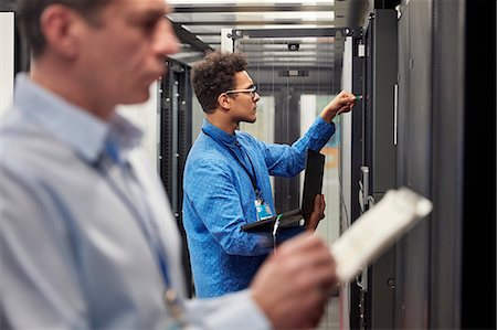 simsearch:6113-06753284,k - Male IT technicians with clipboard and laptop working at panels in server room Stock Photo - Premium Royalty-Free, Code: 6113-09027589