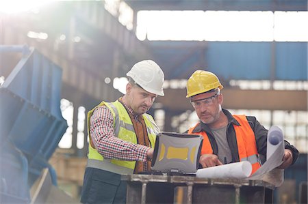 Male foreman and engineer working at laptop with blueprints in factory Stock Photo - Premium Royalty-Free, Code: 6113-09027503