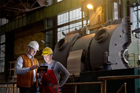 Male engineer and worker using digital tablet in dark factory Stock Photo - Premium Royalty-Free, Code: 6113-09027512