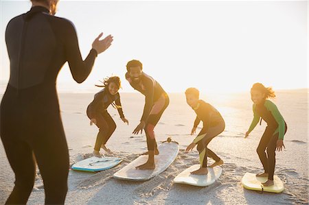 simsearch:6113-08882727,k - Surfer instructor teaching family on surfboards surfing on sunny summer sunset beach Stock Photo - Premium Royalty-Free, Code: 6113-09027659