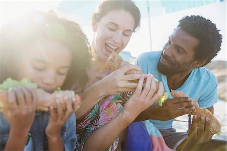 simsearch:6113-09027627,k - Multi-ethnic family eating baguette sandwiches on sunny beach Stock Photo - Premium Royalty-Free, Code: 6113-09027679