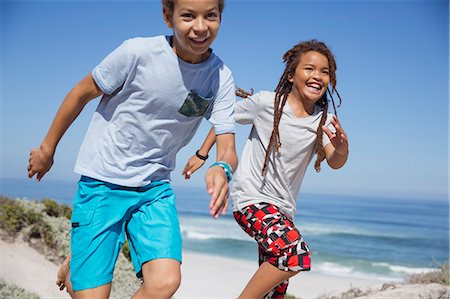 Playful brother and sister running on sunny summer beach Stock Photo - Premium Royalty-Free, Code: 6113-09027685