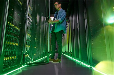 server room - Male IT technician working in dark server room with glowing green panels Stock Photo - Premium Royalty-Free, Code: 6113-09027610