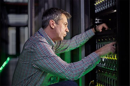 simsearch:6113-09027625,k - Focused male IT technician working at panel in dark server room Stock Photo - Premium Royalty-Free, Code: 6113-09027623