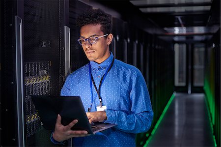 Focused male IT technician using laptop in dark server room Foto de stock - Sin royalties Premium, Código: 6113-09027622