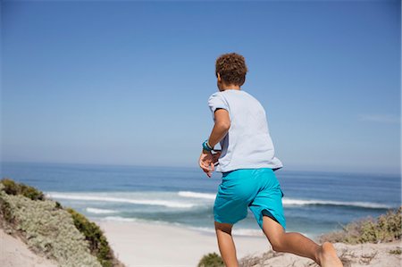 simsearch:649-06352470,k - Pre-adolescent boy running on sunny summer ocean beach Fotografie stock - Premium Royalty-Free, Codice: 6113-09027638