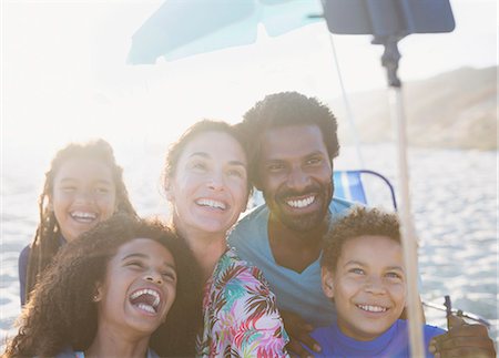 smartphone at beach - Happy, playful multi-ethnic family taking selfie with selfie stick on sunny summer beach Stock Photo - Premium Royalty-Free, Code: 6113-09027763