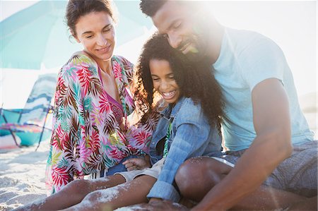 front view of girl playing in the sand - Multi-ethnic family relaxing on sunny summer beach Foto de stock - Sin royalties Premium, Código: 6113-09027767