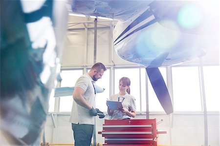 Airplane mechanics with clipboard talking at toolbox in hangar Stock Photo - Premium Royalty-Free, Code: 6113-09027783