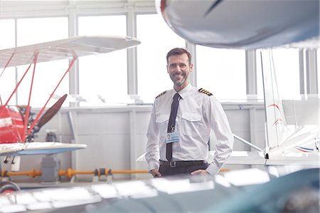 simsearch:6113-09059160,k - Portrait smiling male pilot standing near airplane in hangar Photographie de stock - Premium Libres de Droits, Code: 6113-09027784